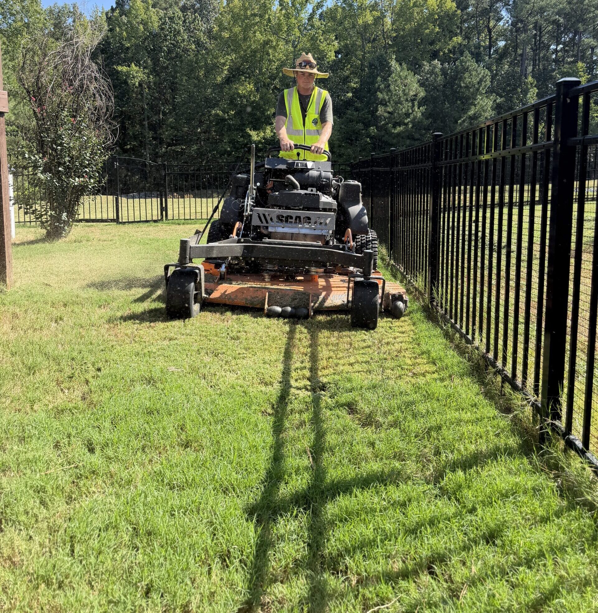Mark mowing the lawn inside a backyard fence on our mower